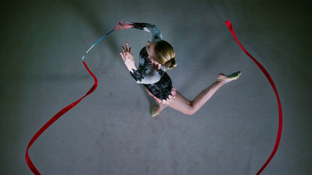 SLO MO LD上方，一个艺术体操运动员旋转着她的红丝带视频素材