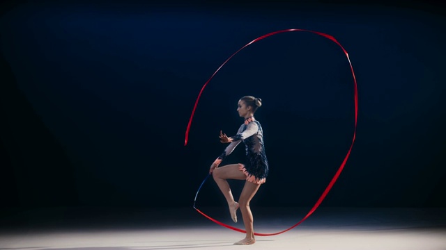 SLO MO LD艺术体操运动员在大范围旋转红丝带时做劈叉跳跃视频下载