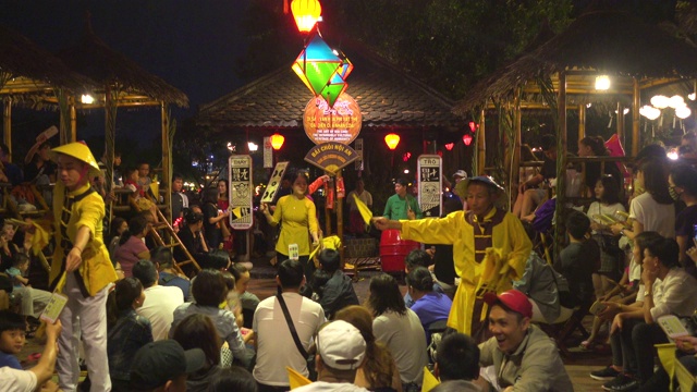晚上的越南传统戏剧。一个被中国灯笼照亮的古老城市。人们坐在地板上视频素材