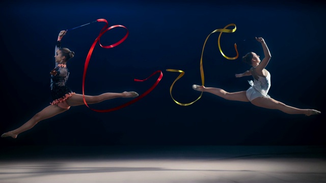 SLO MO SPEED RAMP LD两名艺术体操运动员向相反的方向移动，并在旋转丝带的同时表演分裂跳跃视频素材
