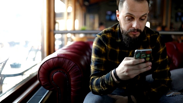 一个年轻人在咖啡馆用智能手机视频素材