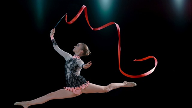 SLO MO SPEED RAMP LD艺术体操运动员旋转她的红丝带并做劈叉跳跃视频素材