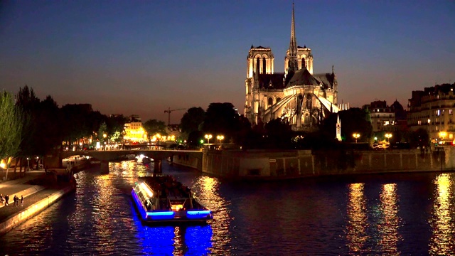夜晚，游客们在巴黎圣母院附近的塞纳河上乘船旅行视频素材