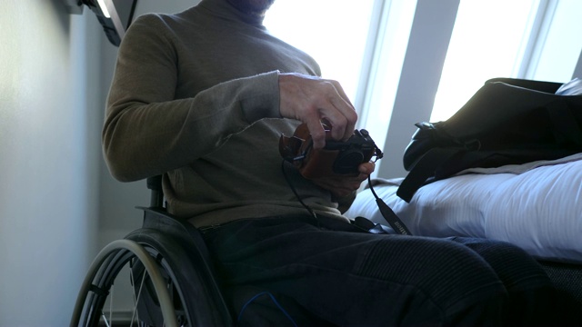 残疾男性客人在酒店房间使用数码相机视频素材