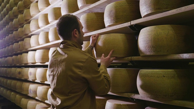 意大利，帕尔马——2018年5月2日——一名奶酪制作者控制着帕尔马奶酪的调味料，这些奶酪必须经过数月的成熟。加工过程遵循古老的意大利传统。视频素材