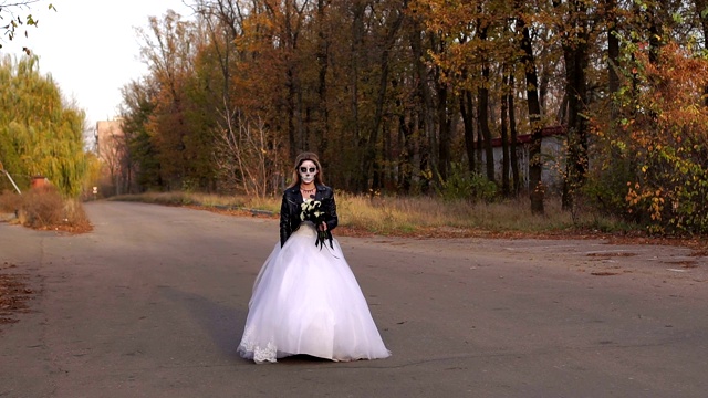 一个化妆成骷髅形状的年轻女孩走在一条空旷的路上视频素材