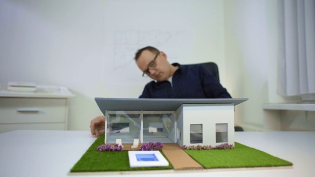 建筑师在办公室的模型房子调整泳池边视频下载