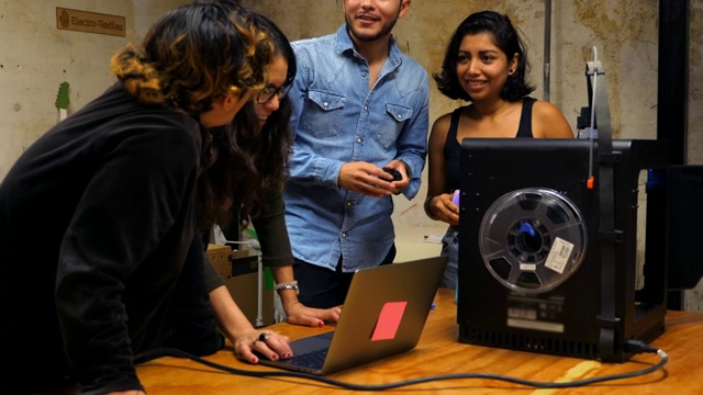 微软工程师在车间检查笔记本电脑上的计划，同时在3D打印机上为项目制作原型视频素材