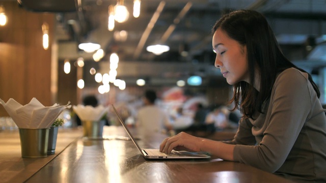 亚洲女人在咖啡馆使用笔记本电脑视频素材