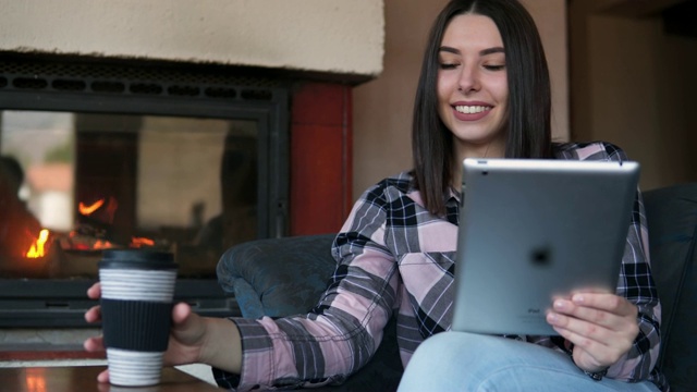 一个女人坐在壁炉旁用着平板电脑视频素材