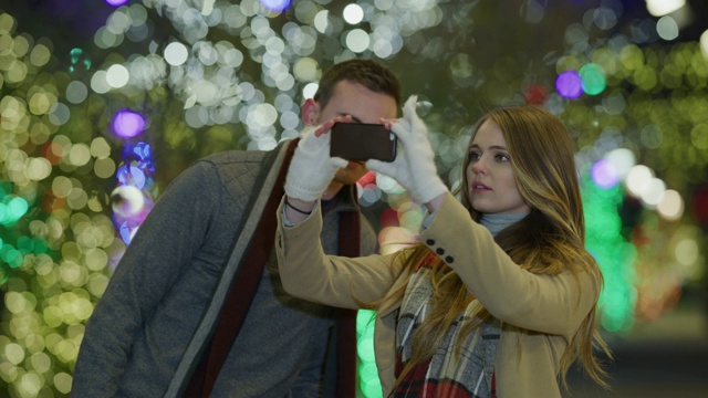 一对夫妇在圣诞节期间用手机在户外拍摄的慢镜头/美国犹他州普罗沃视频素材