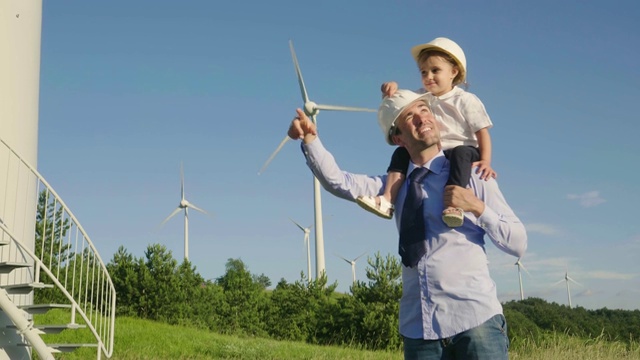 一位工程师父亲，将女儿抱在怀里，在风力涡轮机之间自由奔跑。视频素材