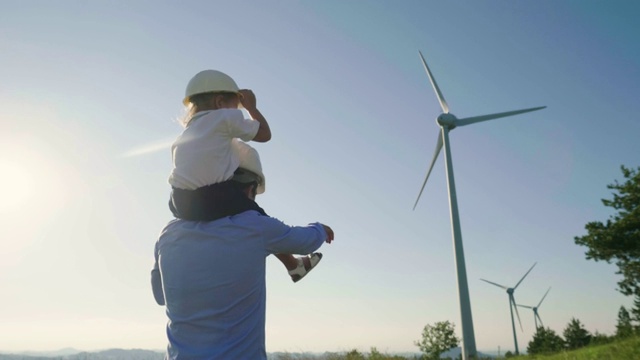 一位工程师父亲，将女儿抱在怀里，在风力涡轮机之间自由奔跑。视频素材