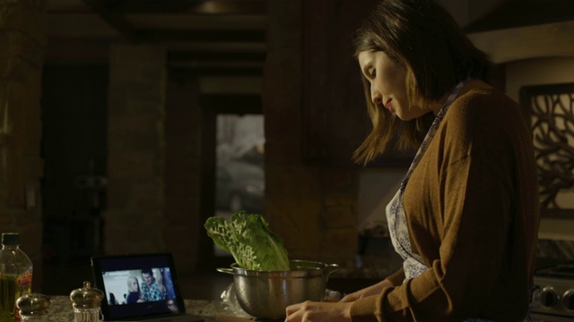 美国犹他州雪松山，一名妇女在厨房边看平板电脑边准备和吃沙拉视频素材