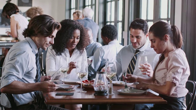 同事们围坐在餐厅的餐桌上，一起享受美食视频素材