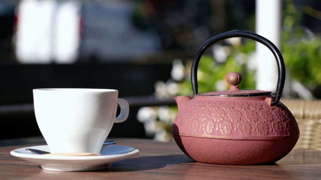 特写的一杯茶与粉红茶壶。那个女人正在法国的一个露台上喝酒。视频下载