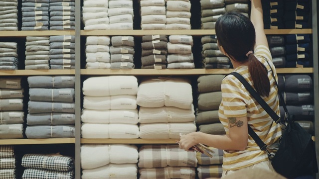 年轻的亚洲妇女在商店买了一块布视频素材