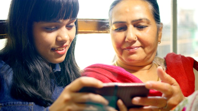 快乐的母女一起使用和分享智能手机。视频素材