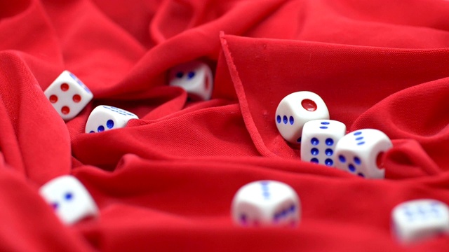 骰子在红缎子上滚动的慢动作视频素材