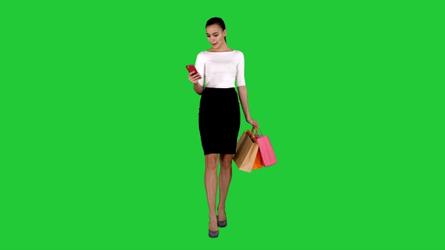 美丽的年轻女子用手机在绿色屏幕上发短信，色度键视频素材