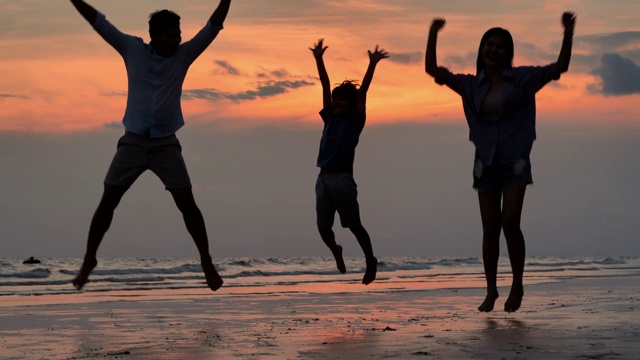 海滩上一家人欢蹦乱跳的剪影。快乐的一家人在海滩上享受暑假。假期——iStock视频素材