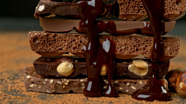 融化的巧克力倒在一堆巧克力和坚果的碎片上。滑块。UHD 4 k视频素材