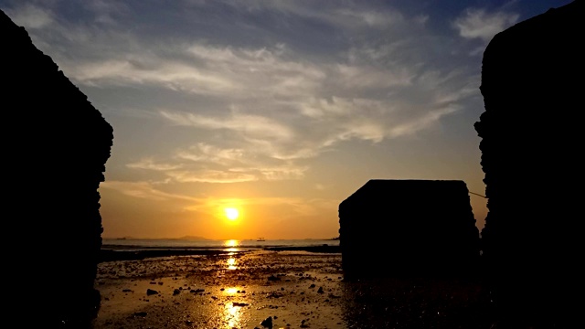 日落的时间流逝在海滩与剪影的混凝土块前景视频素材