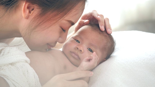 年轻的母亲和刚出生的婴儿在床上视频素材