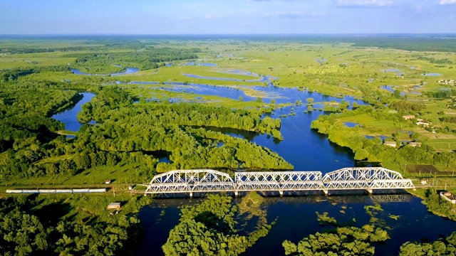 飞在电气化列车上的铁路桥，淹没了草地和美丽的河流。视频下载