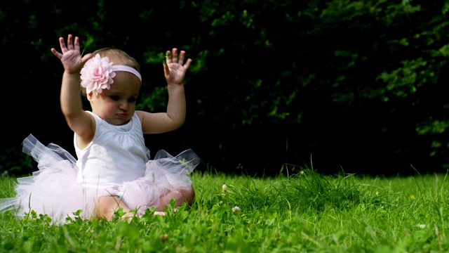 在一个阳光明媚的春日，一个小女孩打扮得像个芭蕾舞演员，在花园里旋转，开心地笑着视频素材