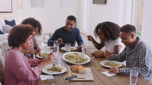 高高在上的幸福黑人家庭坐在餐桌前一起吃饭聊天，近距离视频素材