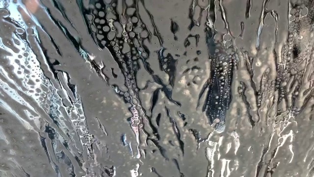 洗车时用肥皂泡沫和蓝色刷子擦车窗视频素材