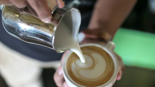 特写的咖啡师加入泡沫牛奶到一杯咖啡视频素材