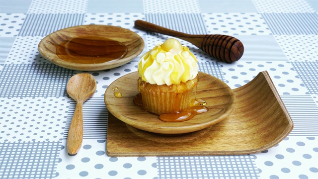 把蜂蜜倒在木盘子里的纸杯蛋糕上视频素材