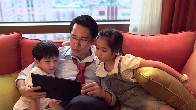 快乐的家人在客厅看平板电脑。他们共度高质量的家庭时光。视频素材
