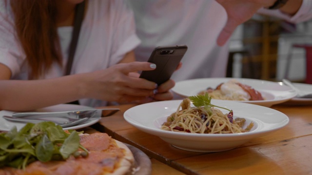 年轻的亚洲夫妇使用手机并分享视频素材