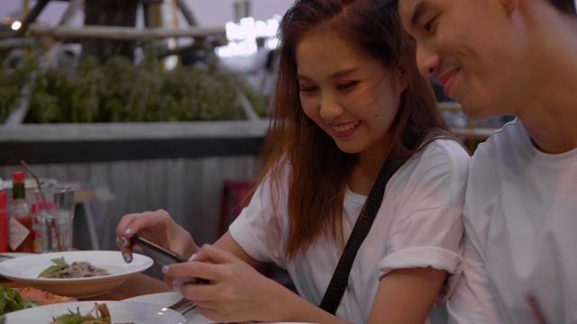 年轻的亚洲夫妇使用手机并分享视频素材