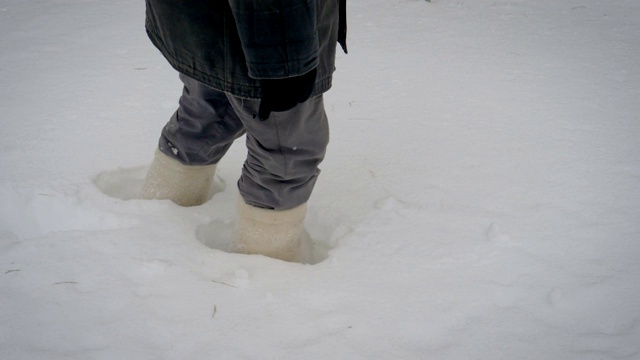 冬天，穿着暖靴的双脚在厚厚的积雪中行走视频下载