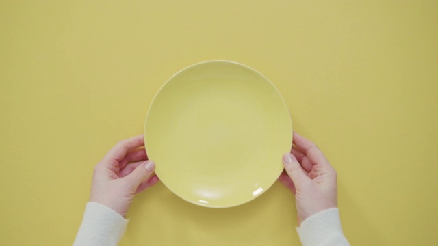 黄色背景上的黄色空盘子。视频下载