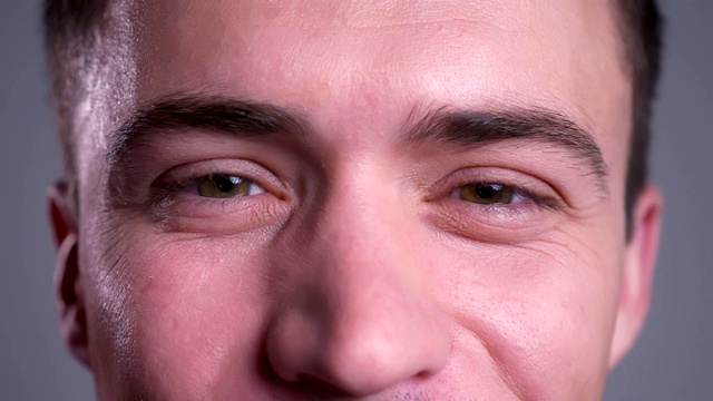 特写有吸引力的白人男性棕色眼睛直视相机微笑的面部表情视频下载