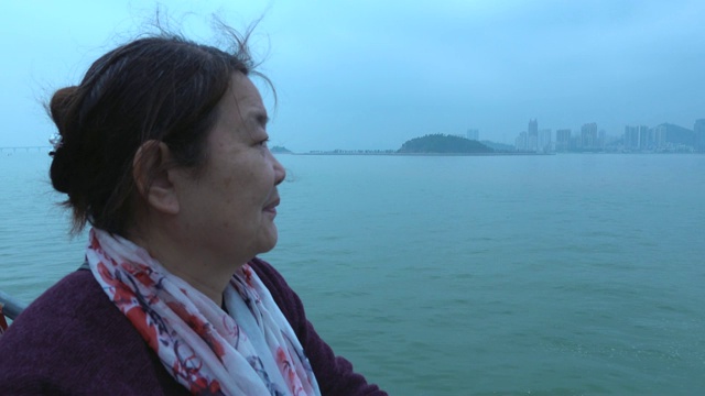 老妇人在游船上欣赏城市风景视频下载