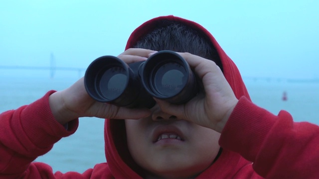 小男孩惊讶地在游船上用双筒望远镜看视频下载