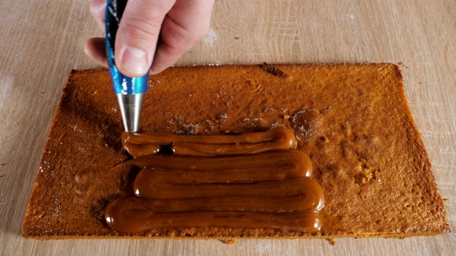 糕点师正在把糕点袋里的焦糖馅放在海绵蛋糕上。视频素材