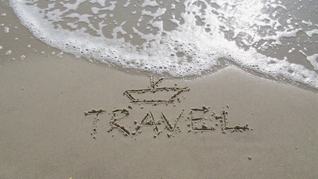 “旅行”这个词写在沙滩上。视频下载