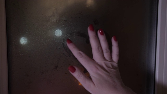 一个女人在一个雾蒙蒙的窗户上画了一颗心视频素材