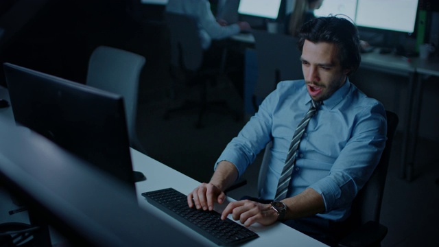 在晚上的办公室工作过度劳累的办公室职员使用桌面电脑打呵欠。疲惫不堪的商人正在完成重要的项目视频素材