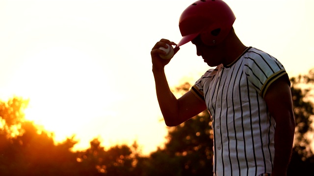 在夕阳下举着棒球的棒球运动员视频下载