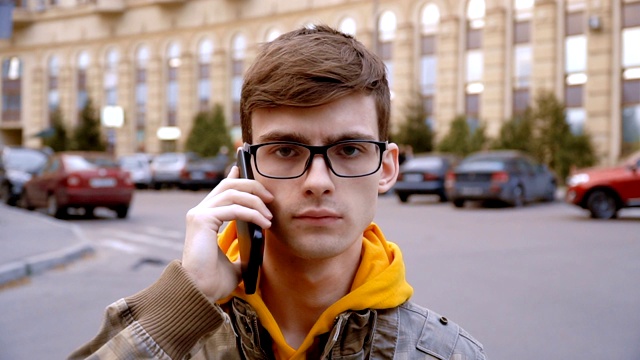 一个年轻人把智能手机放在耳边，慢慢点了点头视频下载