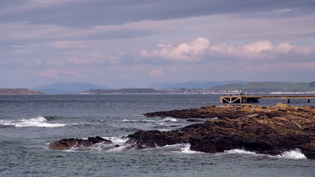 在Seamill Portencross的老码头和苔藓覆盖的岩石上的波浪苏格兰视频素材