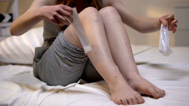 年轻女子脱毛腿用蜡条纹在家，皮肤光滑，身体护理视频素材